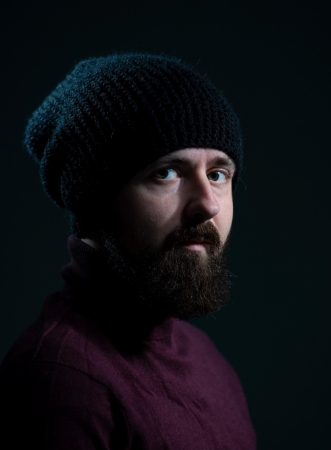 dramatic-portrait-millennial-black-knitted-hat-sweater-dark-background